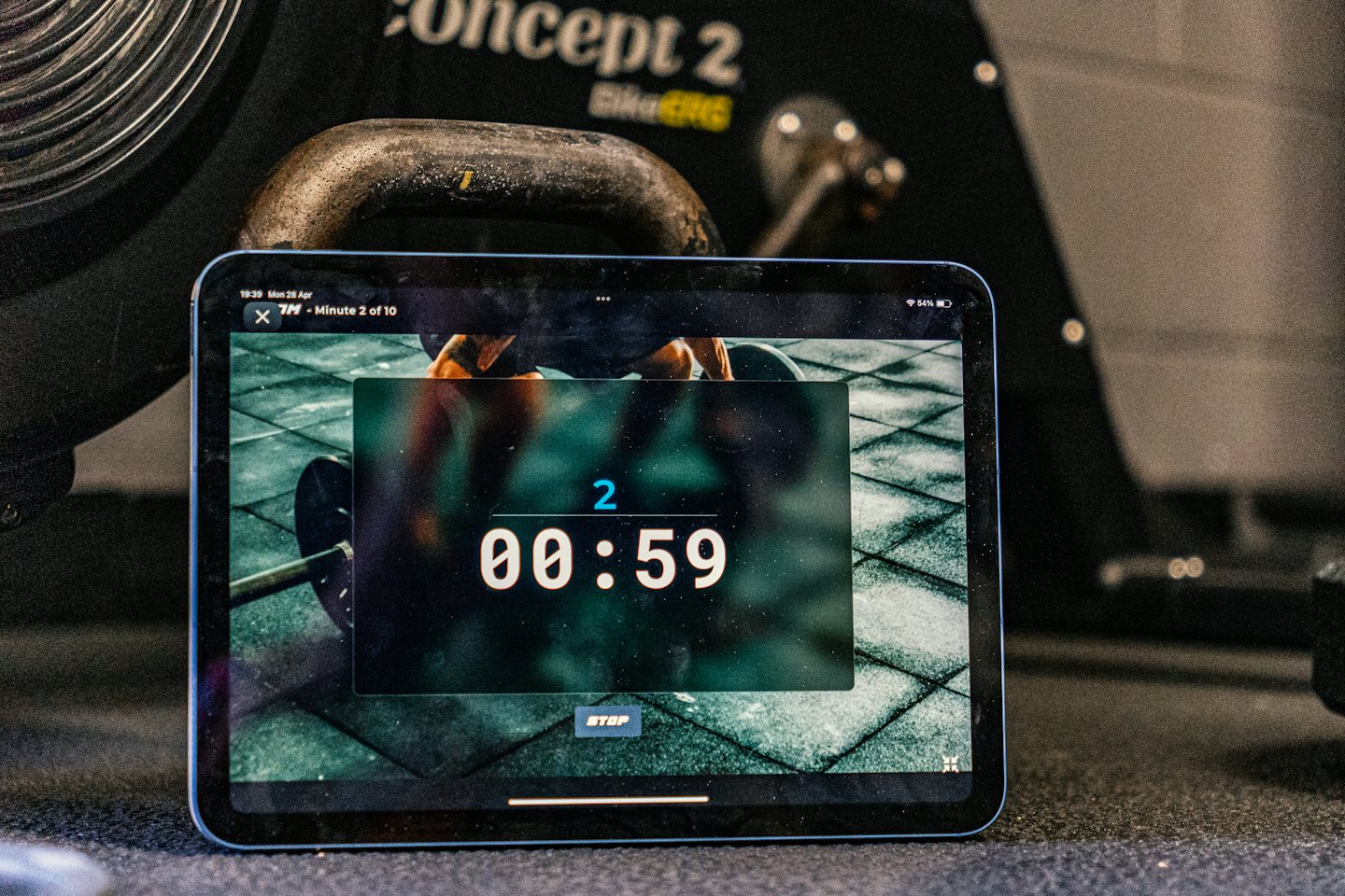 Tablet z timerem treningowym obok roweru treningowego.